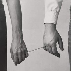 black and white photograph of two people pulling something off the ground with their hands on each other