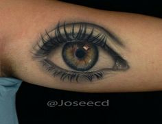 an eye tattoo on the arm with long lashes and large eyelashes is seen in this image