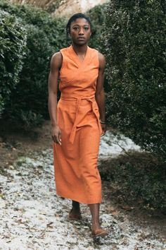 a woman in an orange dress walking down a path