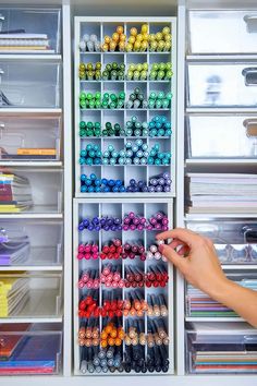 a person's hand is pointing at the drawers in a craft room