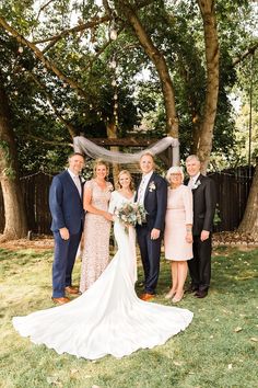 a group of people standing next to each other in front of a wooden structure and trees