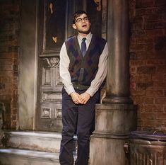 a man standing in front of a building wearing a vest and tie