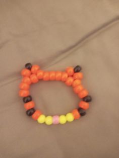 an orange and black beaded bracelet sitting on top of a bed