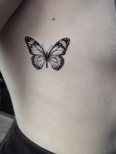 a black and white butterfly tattoo on the back of a woman's stomach,