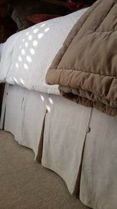 an unmade bed with white sheets and brown pillows