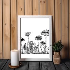 a black and white drawing of mushrooms in the grass next to a candle on a wooden table