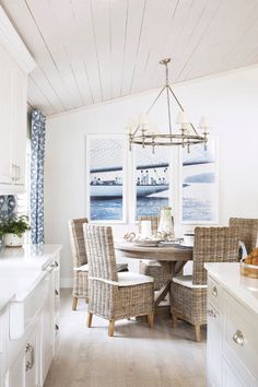 a dining room with white walls and wood flooring in the center is an oval table surrounded by wicker chairs