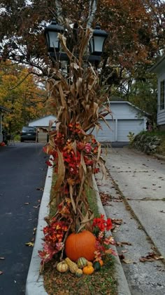 a lamp post decorated with fall foliage and pumpkins on the side of the road