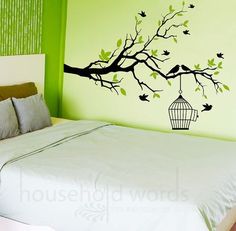 a bed sitting under a tree with a birdcage hanging from it's branch