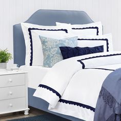 a bed with blue and white comforters in a bedroom next to a night stand