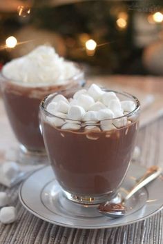 two cups filled with hot chocolate and marshmallows on top of a table