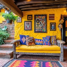 a yellow couch sitting in front of a wall covered in pictures and paintings on it