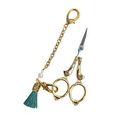 two pairs of scissors with tassels attached to each other on a gold chain