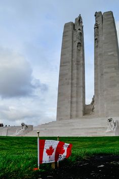 the canadian flag is placed in front of two large stone obelisks with flags on them