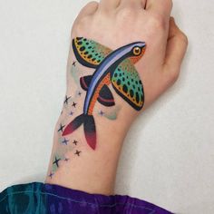 a hand with a colorful fish tattoo on it's left arm and the wrist