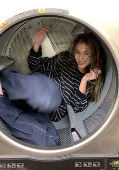 a woman is sitting in a washing machine