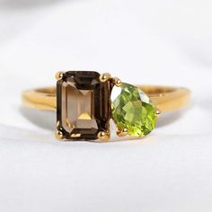 two different colored stones on a yellow gold ring, one is green and the other is brown