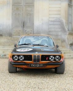 an orange and black car parked in front of a building