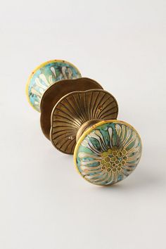 three decorative knobs are shown on a white surface, one is gold and the other is blue