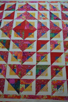 a colorful quilt with many different colors and designs on it's sides, including triangles