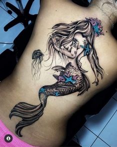 a woman with a tattoo on her stomach is holding a fish in her right side