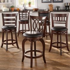 a set of four bar stools in a kitchen with wood flooring and white walls