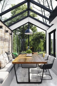 an outdoor dining area with a wooden table and white couches under a glass roof