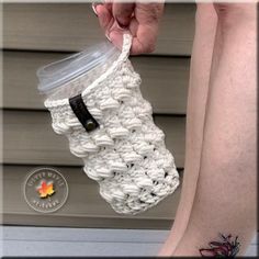 a woman is holding a crocheted coffee cup holder