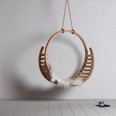 a wooden hanging chair with white feathers on the bottom and one piece of wood below it