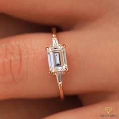 a woman's engagement ring with an emerald cut diamond