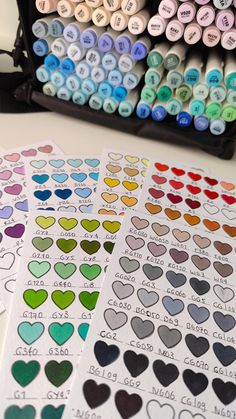 several heart shaped stickers sitting on top of a table next to markers and pens