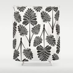 a shower curtain with black and white leaves on it's side, in front of a gray background