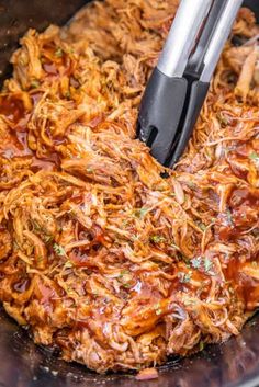 shredded meat in a slow cooker being stirred with an electric pressure cooker tongs