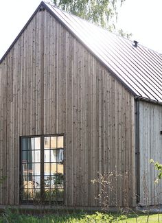 a wooden building sitting next to a lush green field