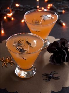 two glasses filled with drinks sitting on top of a table next to a spider web decoration