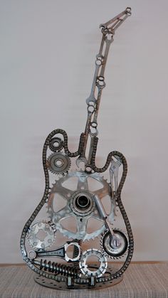 a metal guitar sculpture sitting on top of a wooden table