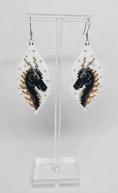 a pair of beaded earrings with a black horse on it's earwires