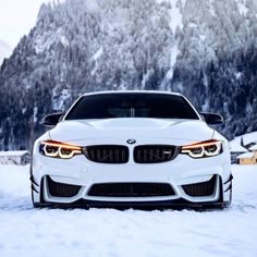 the front end of a white bmw car in the snow