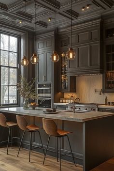 a large kitchen with wooden floors and gray cabinets, along with hanging lights over the island