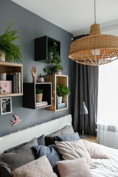 a bed room with a neatly made bed and lots of shelves on the wall above it