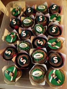 cupcakes with green and white frosting are arranged in a plastic container on a table