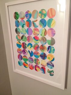 a white framed art piece with colorful circles on it's side, hanging in a bathroom