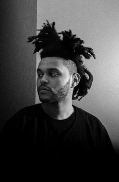 a black and white photo of a man with dreadlocks on his head looking at the camera