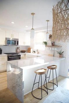 two stools are sitting at the counter in this modern kitchen with white cabinets and an island