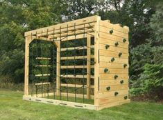 a small wooden structure with lots of plants growing on it's sides in the grass