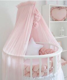 a baby crib with pink bedding and pillows