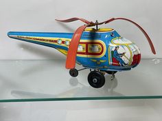 a toy helicopter is on display in a glass case with a red ribbon around it