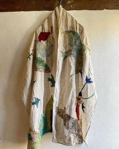 a coat hanging on the wall with animals and birds all over it's fabric