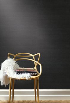 a chair with a book on it sitting in front of a black wall next to a rug