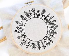 the embroidery hoop has flowers and leaves on it, along with a white t - shirt